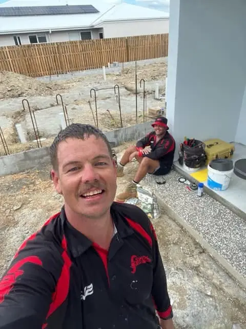 Ricky Skeene smiling on a new home site, with drainage pipework behind him